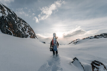 A beautiful shot of a snowboarder walking into the snow on the mountains