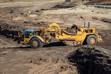 Heavy earthmoving equipment including scapers and motor graders involved in grading operations at a...
