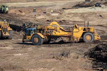 Heavy earthmoving equipment including scapers and motor graders involved in grading operations at a construction site