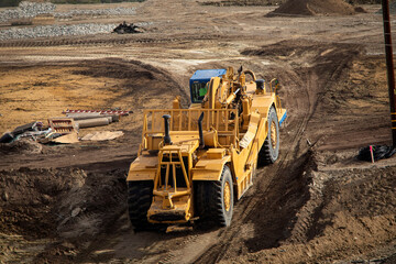 Fototapeta Heavy earthmoving equipment including scapers and motor graders involved in grading operations at a construction site obraz