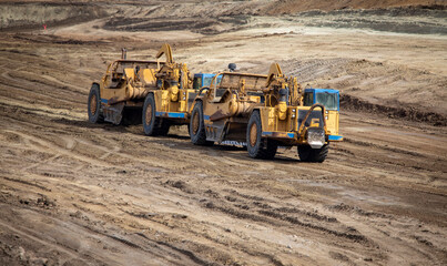Heavy earthmoving equipment including scapers and motor graders involved in grading operations at a...