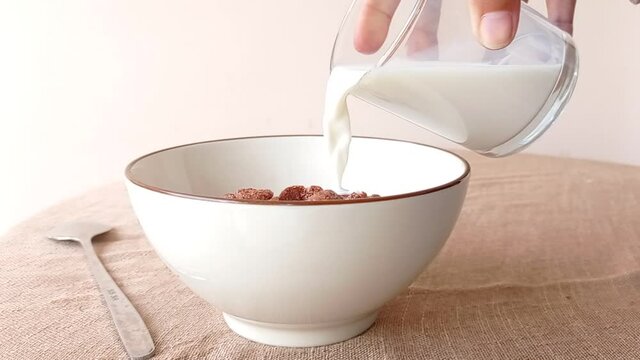 Pouring a glass of milk into a bowl of cereal