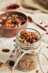 A vertical shot of delicious healthy vegan granola with pecan nuts in a fruity bowl with yogurt on...