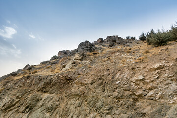 Tochal mountain ridge with rocks and trees in autumn against blue sky, Tehran, Iran. Tochal is a popular recreational region for Tehran's residents
