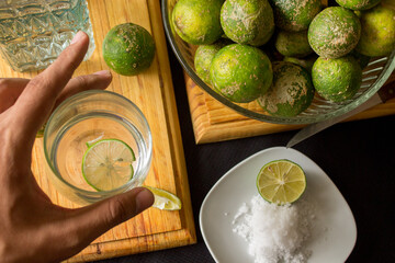 A closeup shot of fresh limes in salt on the table and a man h