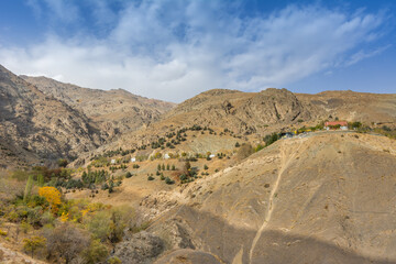 Tochal mountain ridge with rocks and trees in autumn against blue sky, Tehran, Iran. Tochal is a popular recreational region for Tehran's residents