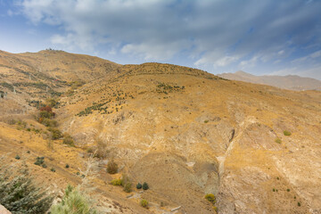 Tochal mountain ridge with rocks and trees in autumn against blue sky, Tehran, Iran. Tochal is a popular recreational region for Tehran's residents