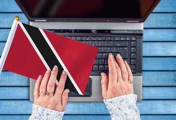 woman hands and flag of Trinidad and Tobago on computer, laptop keyboard 