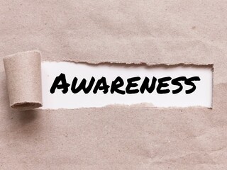 Phrase AWARENESS appearing behind torn brown paper.For background purpose.