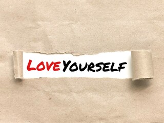 Phrase LOVE YOURSELF appearing behind torn brown paper.For background purpose.