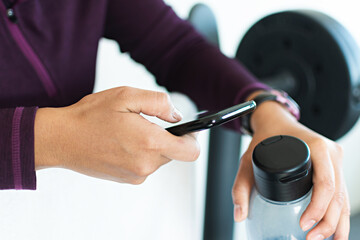 A woman using her smart phone at the gym