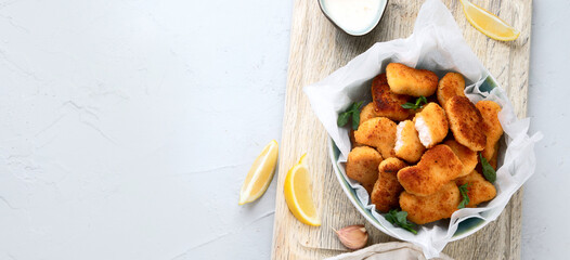 Fried crispy chicken nuggets with ketchup on wooden board