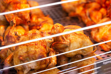 Grilled chicken with a golden brown crust on the display case. Close-up.