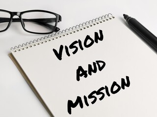 Text VISION AND MISSION on notebook with marker pen and eye glasses.Business concept.