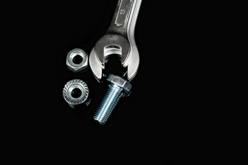 several wrenches next to nuts and bolts on a black background