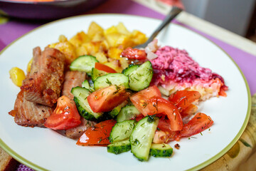 a plate with fried tuna, potatoes and fresh salad on the table