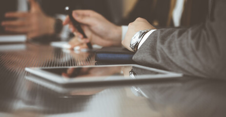 Unknown businessmen and woman sitting, working and discussing questions at meeting in modern office, close-up