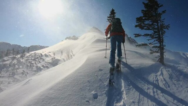 A man on skis in the mountains in a strong blizzard rises up. Adventure, freedom, challenge. Element in the mountains.