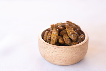 
silkworm pupa in wooden bow as edible insects on white background, high protein insect