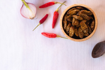 
silkworm pupa in wooden bow as edible insects on white background, high protein insect