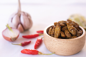 
silkworm pupa in wooden bow as edible insects on white background, high protein insect