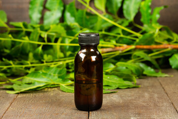 neem oil in bottle and neem leaf on wooden background.