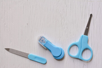 Scissors, clipper and soother on light white table. White color background. Simple tools for baby nail cutting. Empty place for text. Closeup.