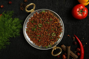 delicious cooked fried traditional minced beef keema fry North Indian Pakistani food black background curry served bronze bowl 