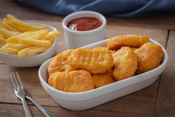 Crispy chicken nuggets and french fries in bowl.