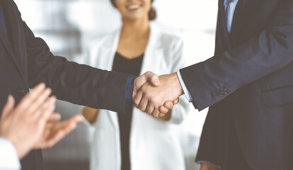 Unknown businesspeople are shaking their hands after signing a contract at meeting, close-up. Business communication concept