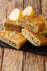 Mutabbaq is a delicious stuffed paratha with spicy minced meat, which is a popular street food in Saudia Arabia closeup in the board on the table. vertical 