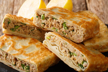 Saudi Street Food Mutabbaq with meat, egg and green onion closeup in the board on the table. horizontal