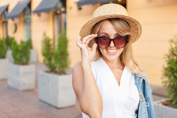Street fashion, young stylish cheerful woman in sunglasses and hat in the city