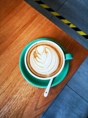 Coffee in a green cup on brown wooden table 