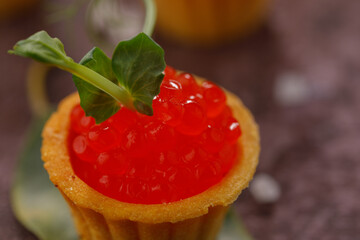 Tartlets with red caviar. Holiday concept. Still life with greenery decor. Close-up.