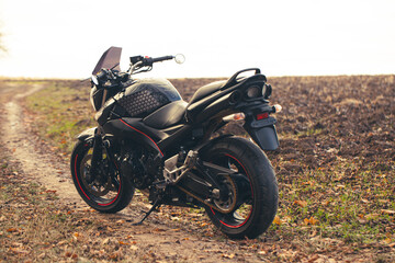 Black stylish sport motorcycle in autumn forest.