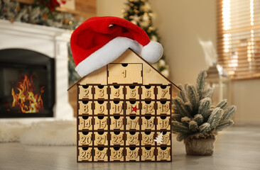 Wooden house shaped Advent calendar in room decorated for New Year