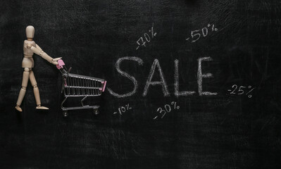 Puppet with shopping trolley, Sale word chalk hand drawn on blackboard
