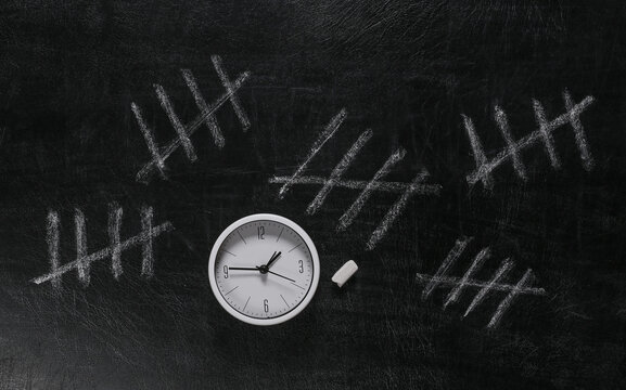 Chalk Tally Number Counting Mark on the Classroom Blackboard with clock. The passage time concept