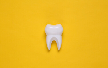 Fake tooth on yellow background. Top view