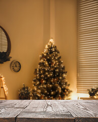 Empty wooden surface and blurred Christmas tree in room on background, bokeh effect. Space for design