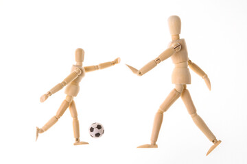 Wooden puppets dummy playing soccer isolated on white background