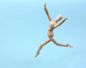 Cheerful wooden puppet jumping on blue background