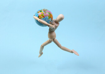 Wooden puppet with globe on blue background