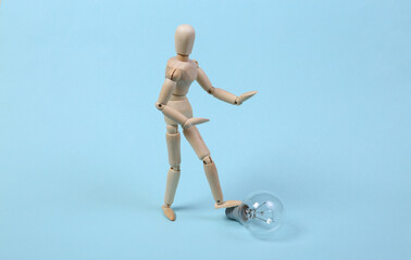 Wooden puppet and light bulb on a blue background.