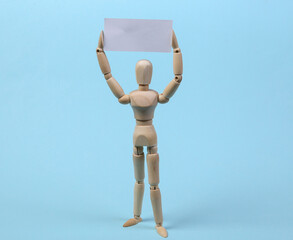 Wooden mannequin puppet standing with blank sign protesting on blue background