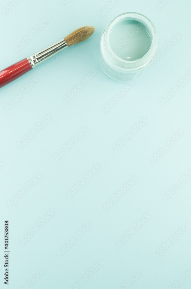 Poster a vertical top view of a paintbrush and empty container isolated on light blue background with cop