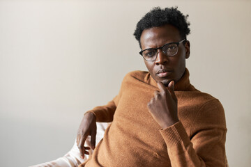 Ideas, thoughts and concentration. Handsome serious young African man in sweater touching chin with...