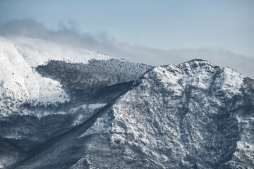 View from above, stunning panoramic view of a snow capped mountain range during a cloudy day. Italy.