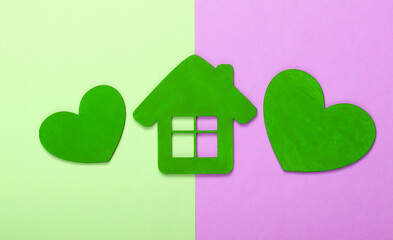 Green wooden hearts with a house figurine on pink green pastel background
